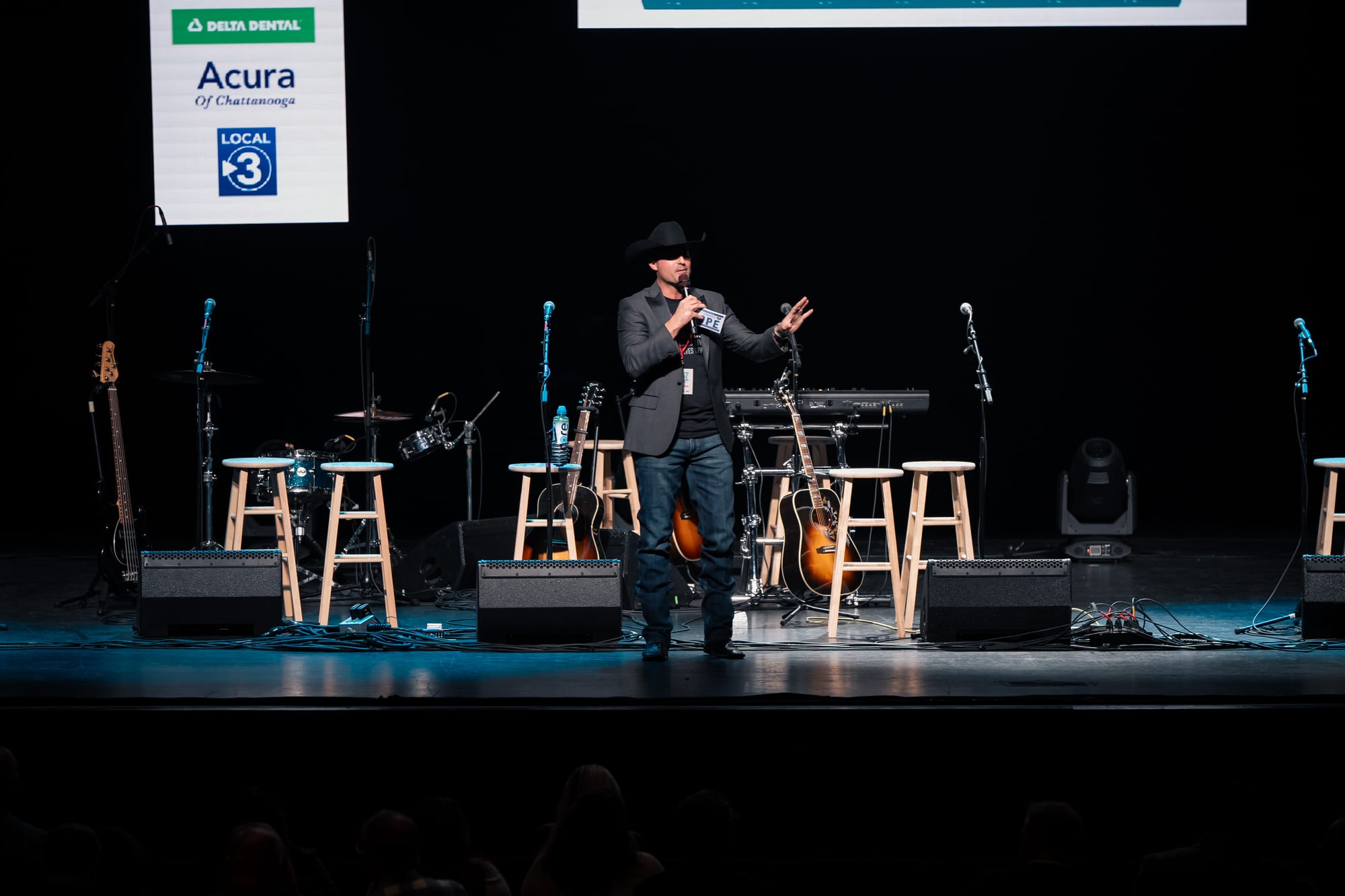 Host speaking on stage in front of the Hope banner