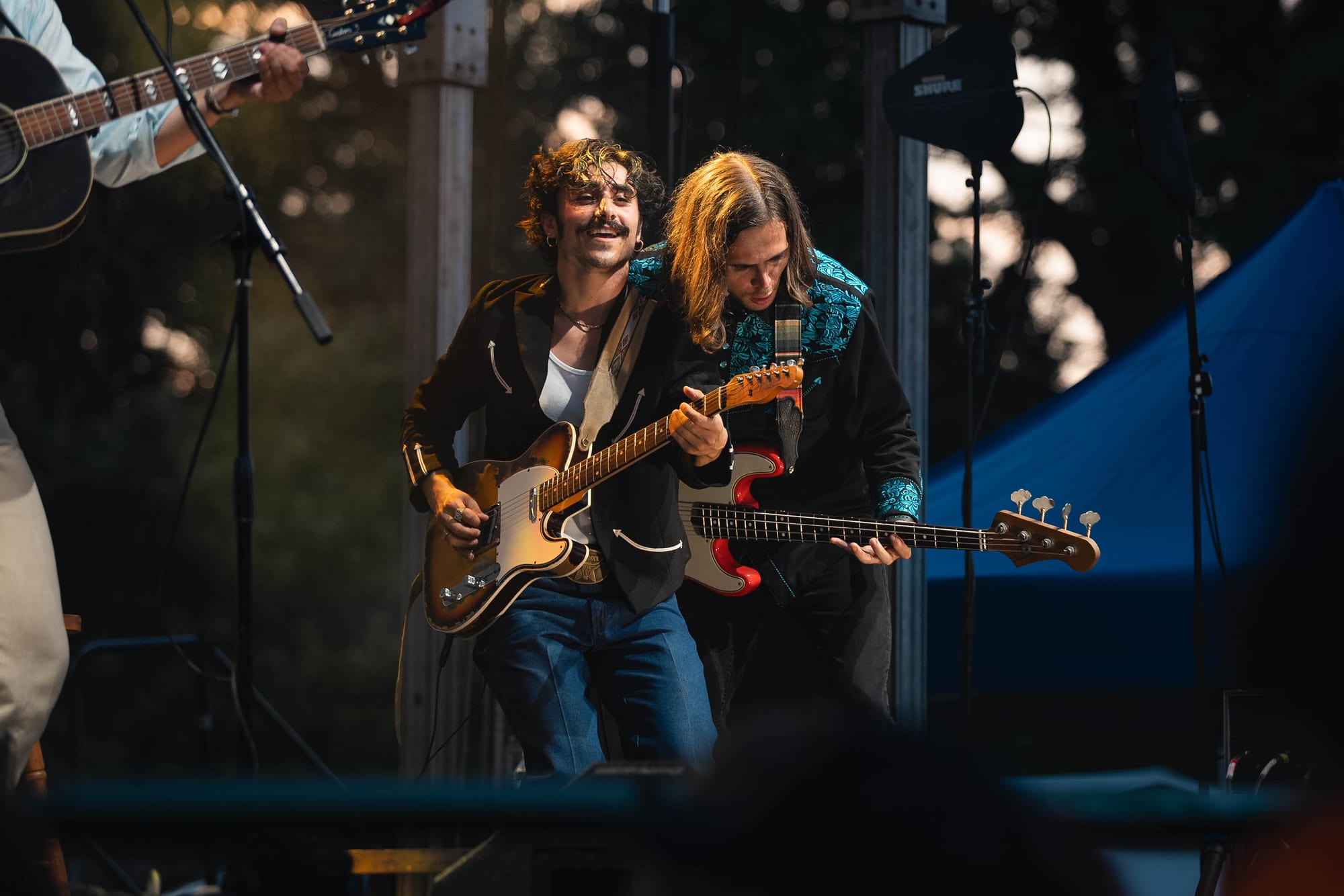 Two guitarists performing together at sunset