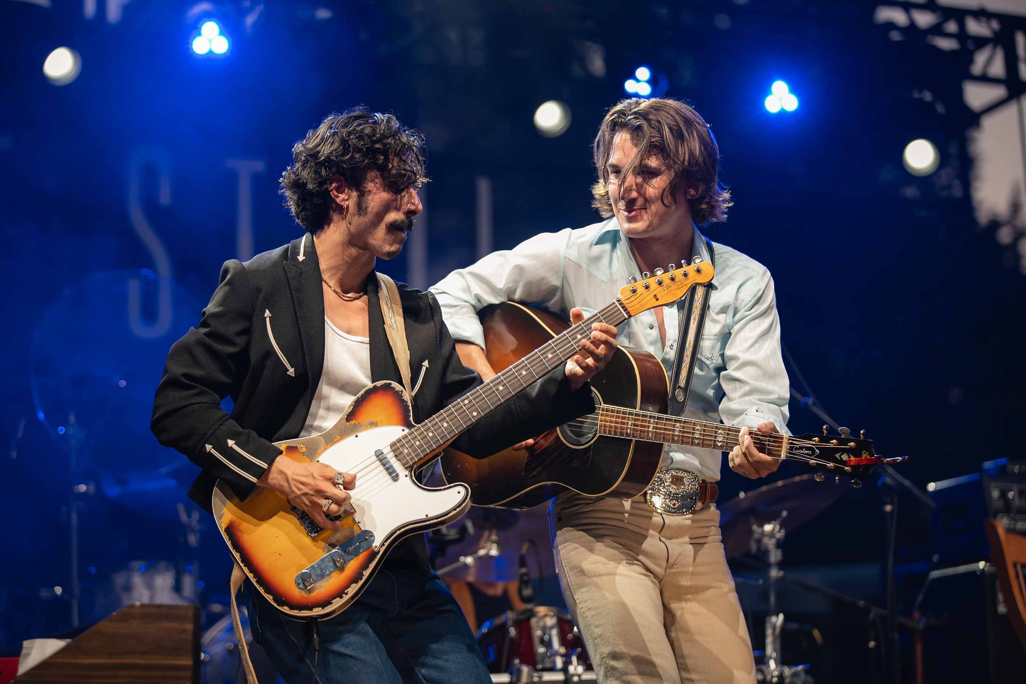 Two band members performing together under stage lights