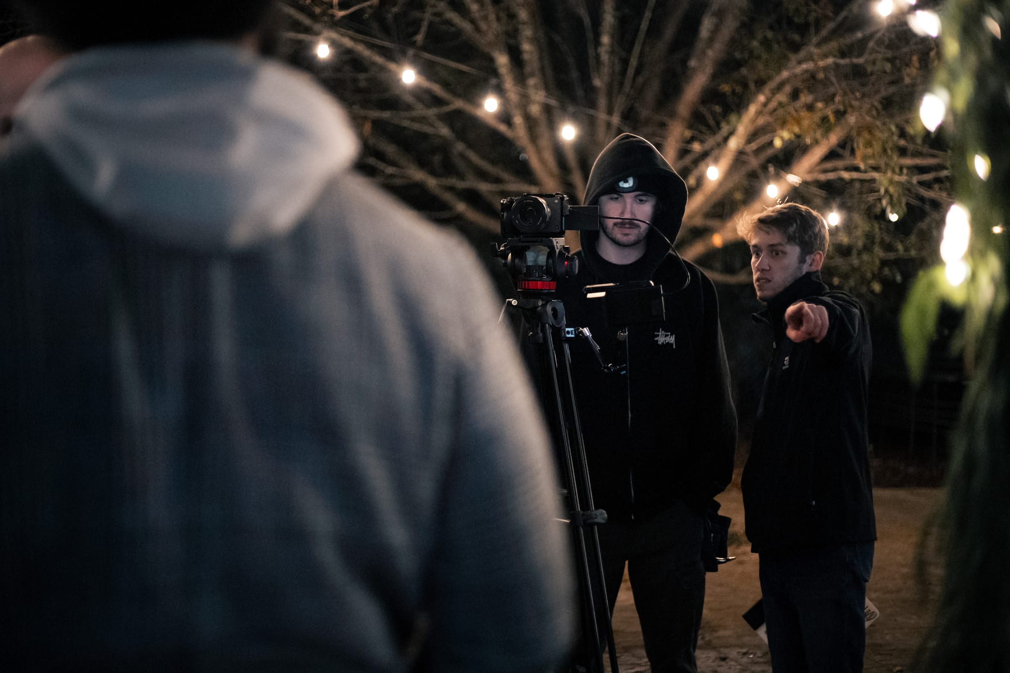 Camera operator behind a tripod-mounted camera at night