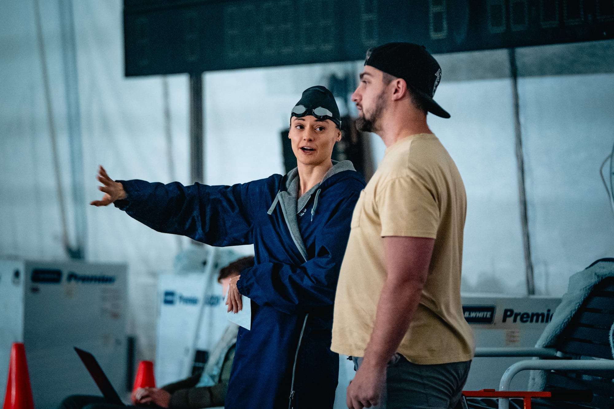 Director pointing out direction to swimmer on starting blocks