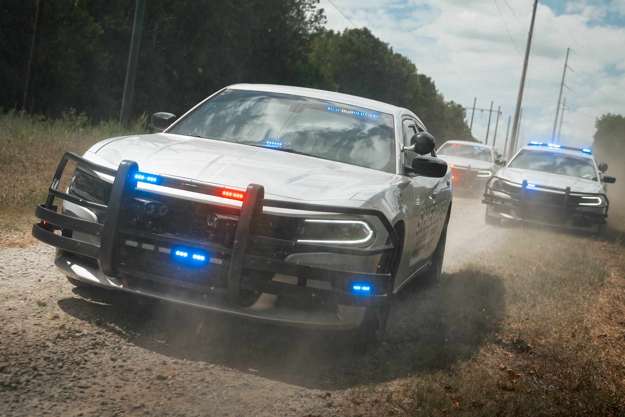 Sheriff vehicle convoy on dirt road